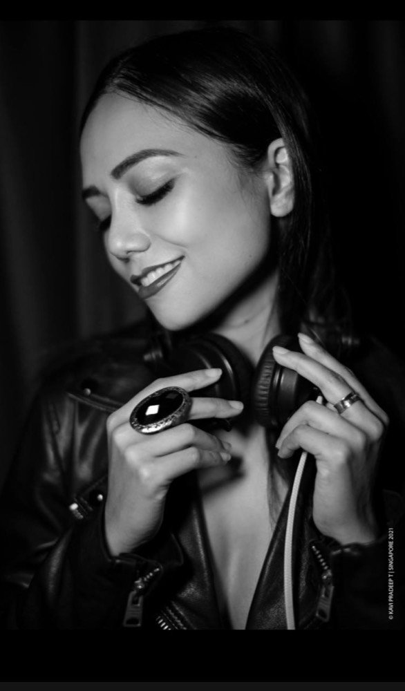 Black-and-white portrait — headphones resting around her neck, leather jacket